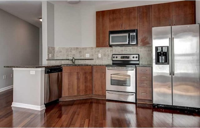 kitchen featuring sink, stainless steel appliances, dark wood-type flooring, and dark stone countertops