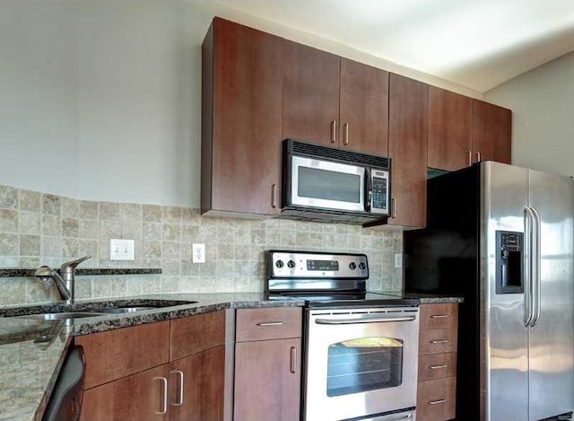 kitchen featuring backsplash, dark stone countertops, sink, and appliances with stainless steel finishes