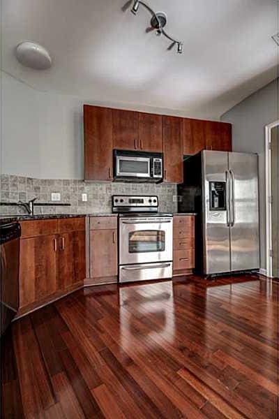 kitchen featuring decorative backsplash, stainless steel appliances, dark wood-type flooring, and sink