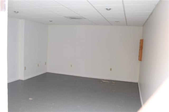 spare room with a paneled ceiling and concrete floors