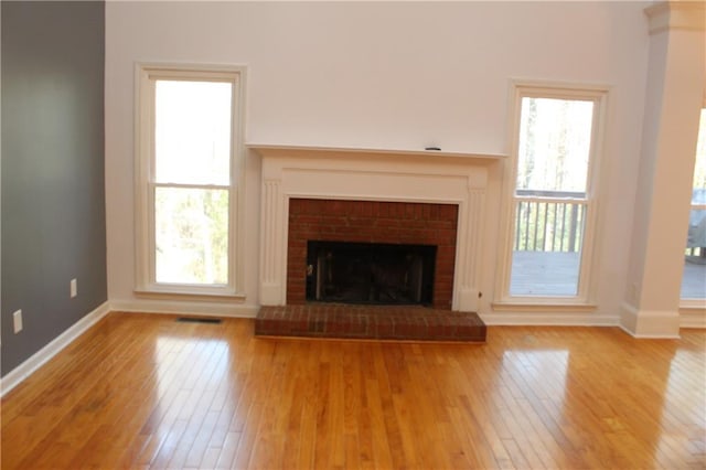 unfurnished living room featuring a brick fireplace and light hardwood / wood-style flooring