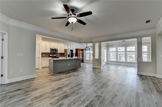 kitchen with crown molding, a center island with sink, visible vents, appliances with stainless steel finishes, and open floor plan