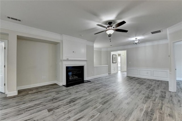 unfurnished living room with visible vents, ornamental molding, a glass covered fireplace, light wood-style floors, and a ceiling fan