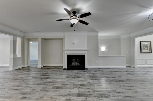 unfurnished living room with ceiling fan, wood finished floors, a fireplace with flush hearth, visible vents, and crown molding