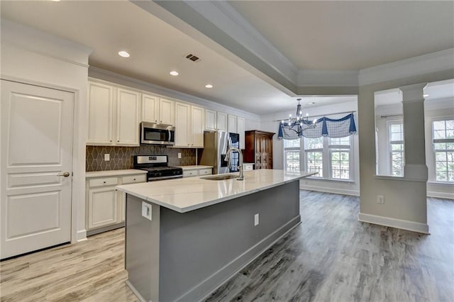 kitchen with stainless steel appliances, a sink, visible vents, a large island, and crown molding