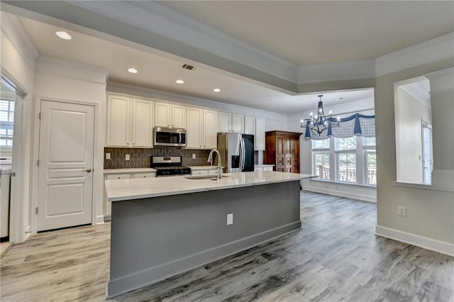 kitchen with stainless steel appliances, ornamental molding, a sink, and tasteful backsplash