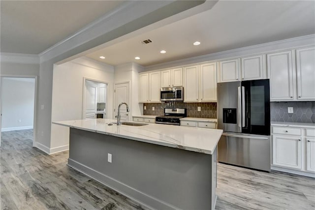 kitchen with crown molding, visible vents, appliances with stainless steel finishes, a sink, and an island with sink