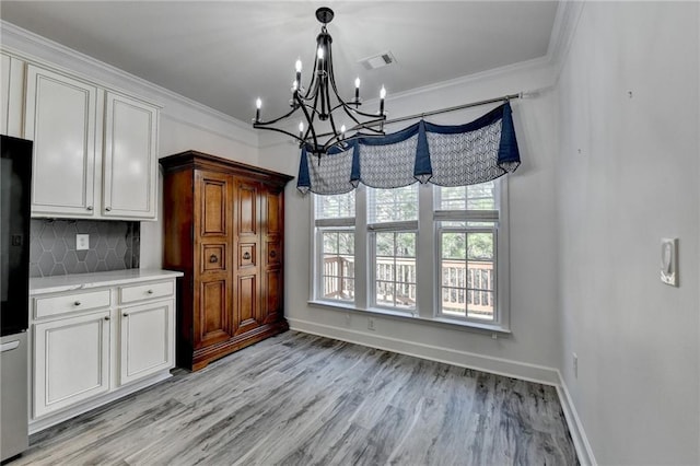 unfurnished dining area with ornamental molding, light wood-type flooring, visible vents, and baseboards