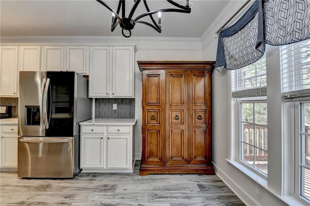 kitchen featuring backsplash, ornamental molding, stainless steel refrigerator with ice dispenser, and light countertops