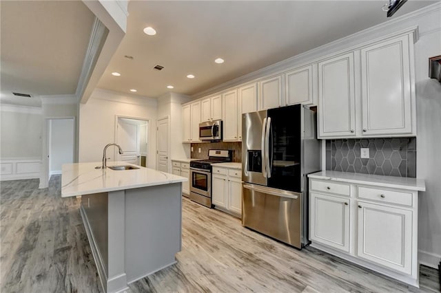 kitchen with light wood-type flooring, a center island with sink, stainless steel appliances, and a sink