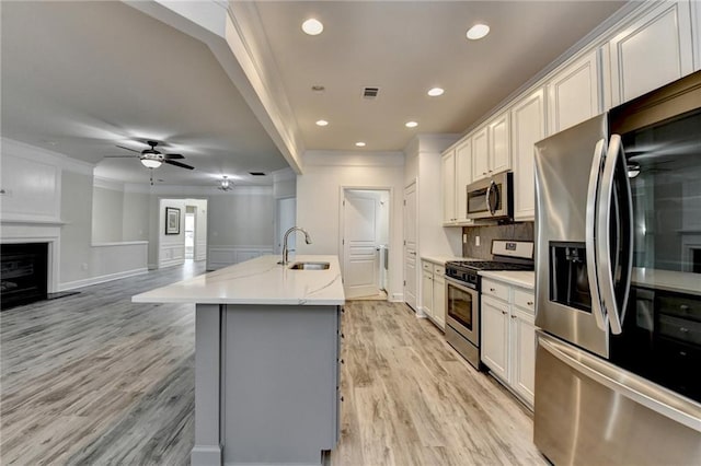 kitchen with light wood finished floors, visible vents, backsplash, appliances with stainless steel finishes, and a sink