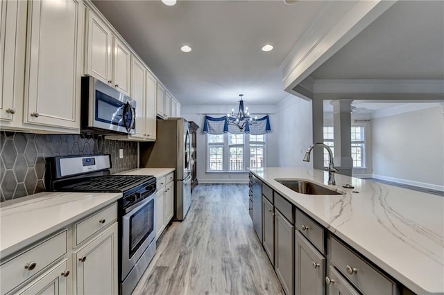 kitchen featuring crown molding, stainless steel appliances, decorative backsplash, a sink, and ornate columns