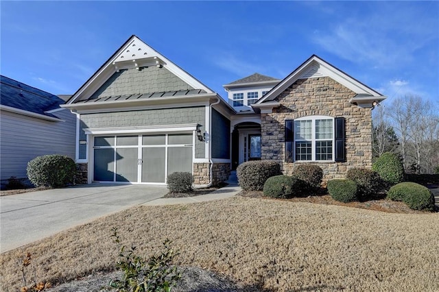 craftsman-style home featuring driveway, stone siding, a standing seam roof, and an attached garage