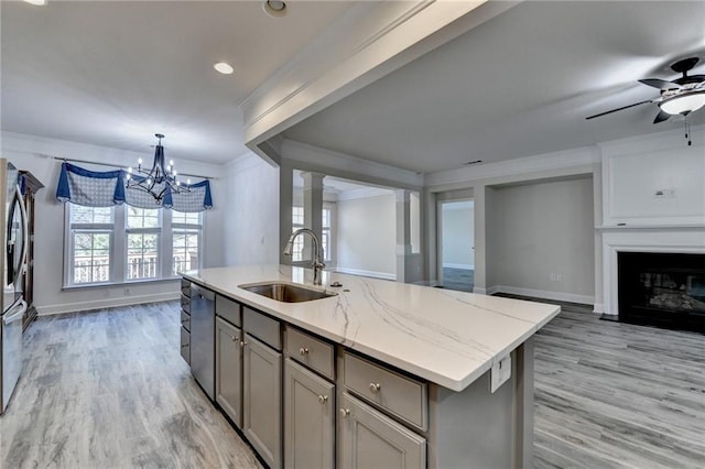 kitchen featuring gray cabinetry, a fireplace with flush hearth, a sink, open floor plan, and appliances with stainless steel finishes