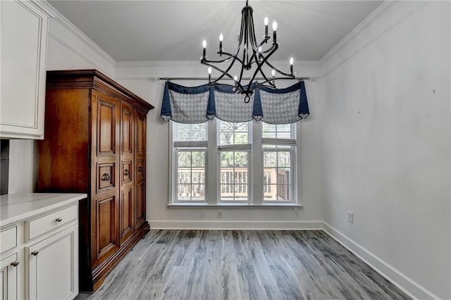 unfurnished dining area featuring light wood-type flooring, an inviting chandelier, baseboards, and ornamental molding