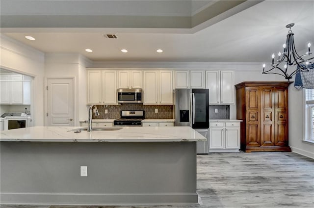 kitchen featuring appliances with stainless steel finishes, backsplash, a sink, and visible vents