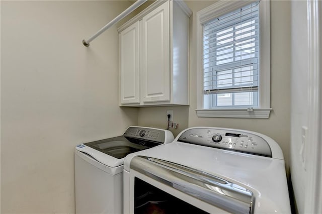 clothes washing area featuring washing machine and dryer and cabinet space