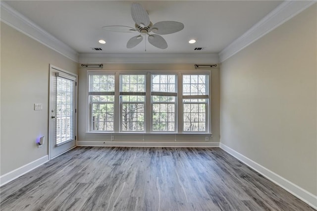 spare room with ornamental molding, visible vents, baseboards, and wood finished floors