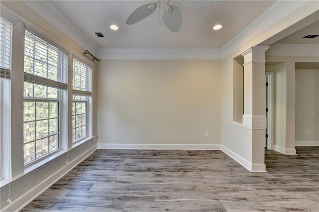 unfurnished room with baseboards, wood finished floors, visible vents, and crown molding