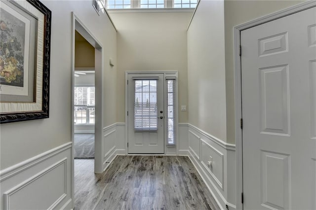 foyer with a wainscoted wall, visible vents, light wood-style flooring, and a decorative wall