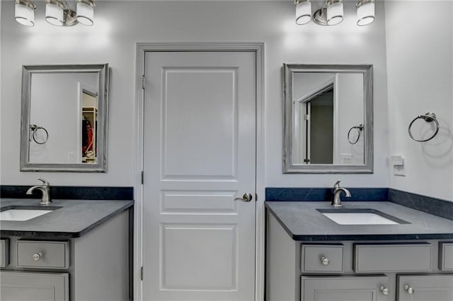 bathroom with a closet, two vanities, and a sink