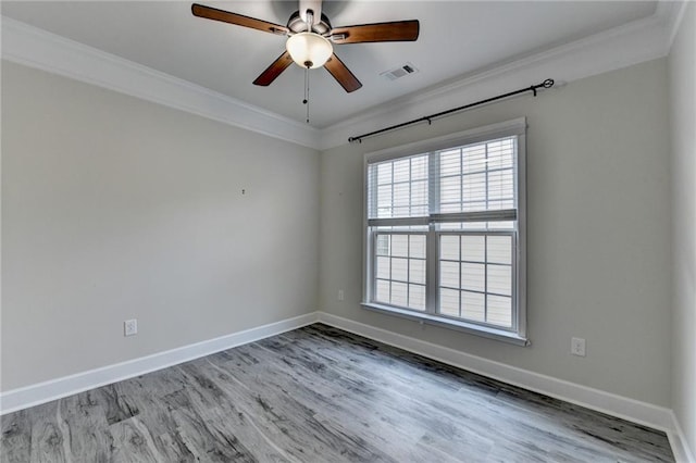 spare room with ceiling fan, wood finished floors, visible vents, baseboards, and ornamental molding