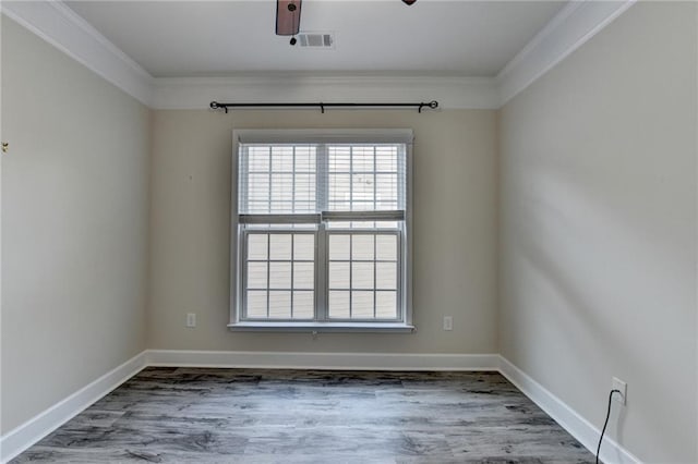 empty room featuring wood finished floors, visible vents, and baseboards