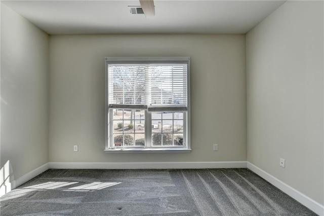 empty room featuring carpet floors, a healthy amount of sunlight, visible vents, and baseboards