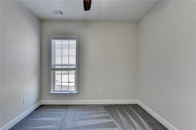 empty room featuring dark colored carpet, visible vents, and baseboards