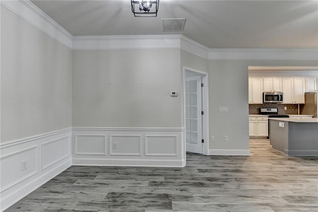 kitchen featuring crown molding, tasteful backsplash, visible vents, appliances with stainless steel finishes, and wood finished floors