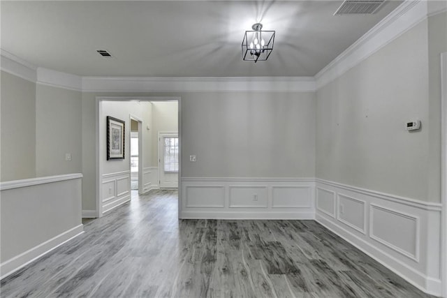 unfurnished dining area featuring ornamental molding, visible vents, a notable chandelier, and wood finished floors