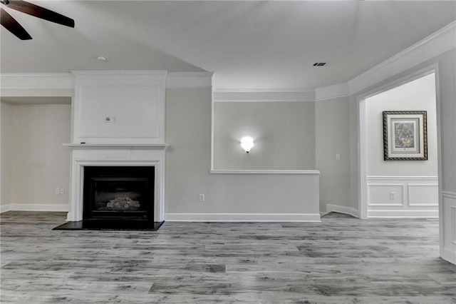 unfurnished living room with a large fireplace, wood finished floors, a ceiling fan, and crown molding