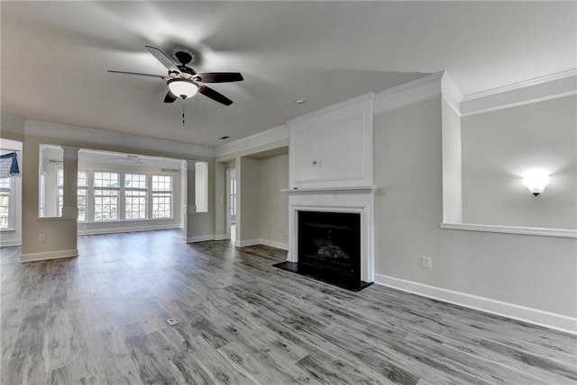 unfurnished living room featuring ornamental molding, a fireplace with raised hearth, ceiling fan, and wood finished floors