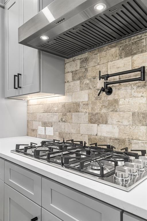 407 Estates View Dr, Acworth, GA 30101 - kitchen view of extractor fan, pot filler, light countertops, stainless steel gas stovetop, and tasteful backsplash