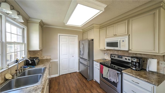 kitchen with dark wood finished floors, a sink, tasteful backsplash, appliances with stainless steel finishes, and cream cabinets