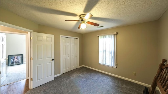 unfurnished bedroom with baseboards, visible vents, dark carpet, and a closet