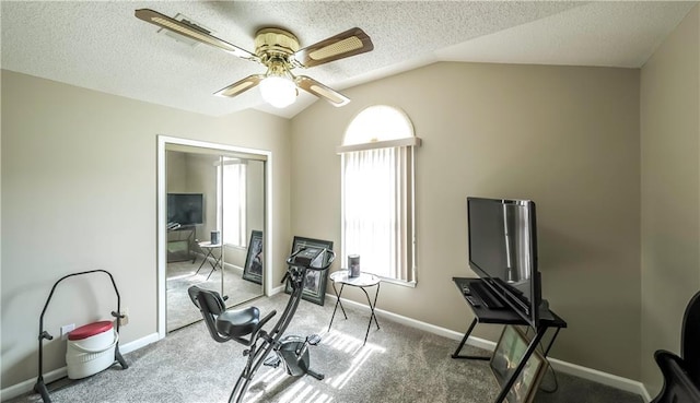 exercise room featuring vaulted ceiling, a textured ceiling, baseboards, and ceiling fan