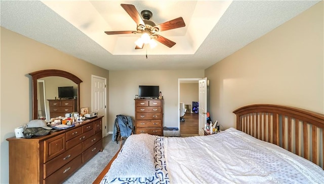 bedroom with a tray ceiling, carpet flooring, and a ceiling fan