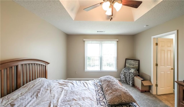 bedroom featuring a textured ceiling, visible vents, light colored carpet, and ceiling fan