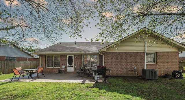 rear view of property featuring fence, a yard, central air condition unit, a patio, and brick siding