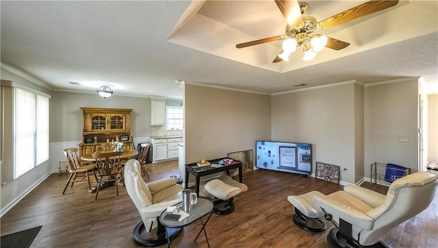 living area featuring ceiling fan, dark wood-style flooring, ornamental molding, and a textured ceiling