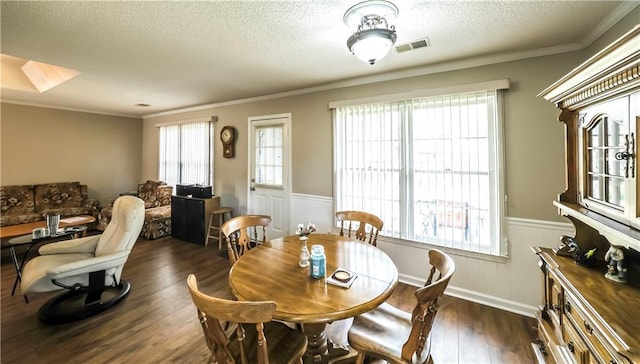 dining space with dark wood-style floors, visible vents, ornamental molding, wainscoting, and a textured ceiling