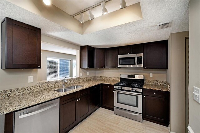 kitchen with stainless steel appliances, a raised ceiling, sink, and dark brown cabinetry