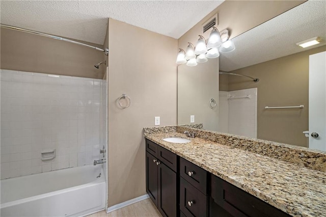 bathroom featuring vanity, tub / shower combination, and a textured ceiling