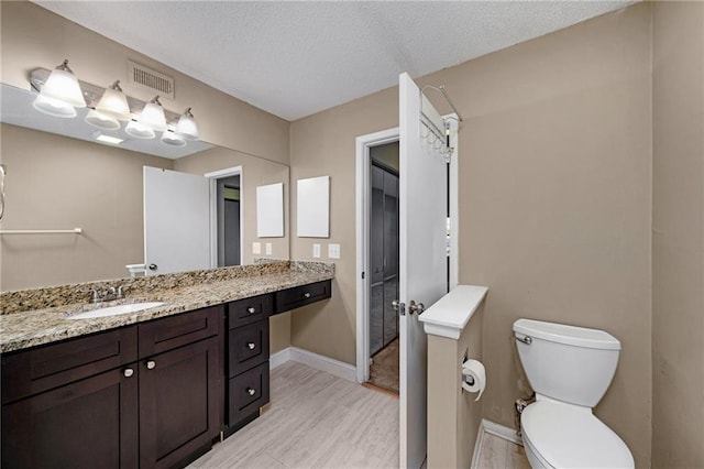 bathroom featuring vanity, a textured ceiling, and toilet