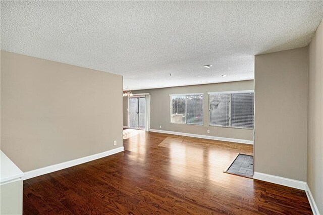 empty room with dark hardwood / wood-style flooring and a textured ceiling