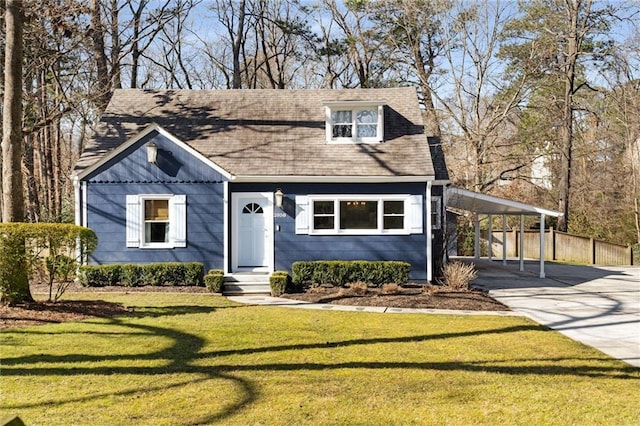 view of front facade with an attached carport, roof with shingles, driveway, and a front yard