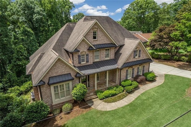 view of front of property with metal roof, a porch, a standing seam roof, and a front yard