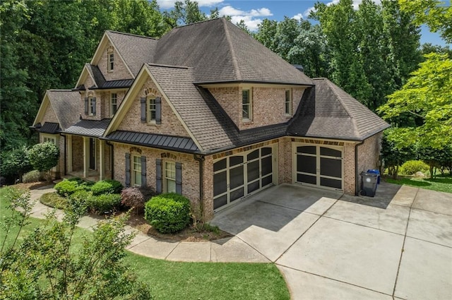 view of front of house with metal roof, an attached garage, brick siding, driveway, and a standing seam roof