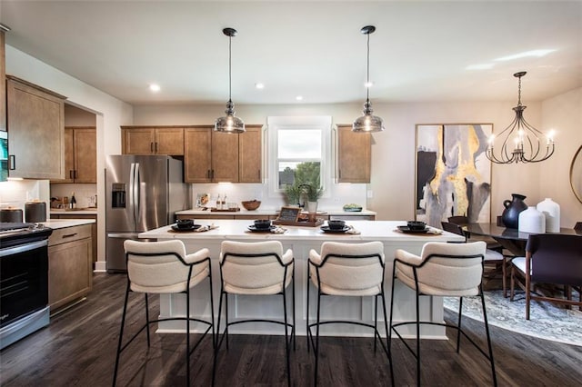 kitchen featuring stainless steel fridge, stove, dark wood-type flooring, and decorative light fixtures